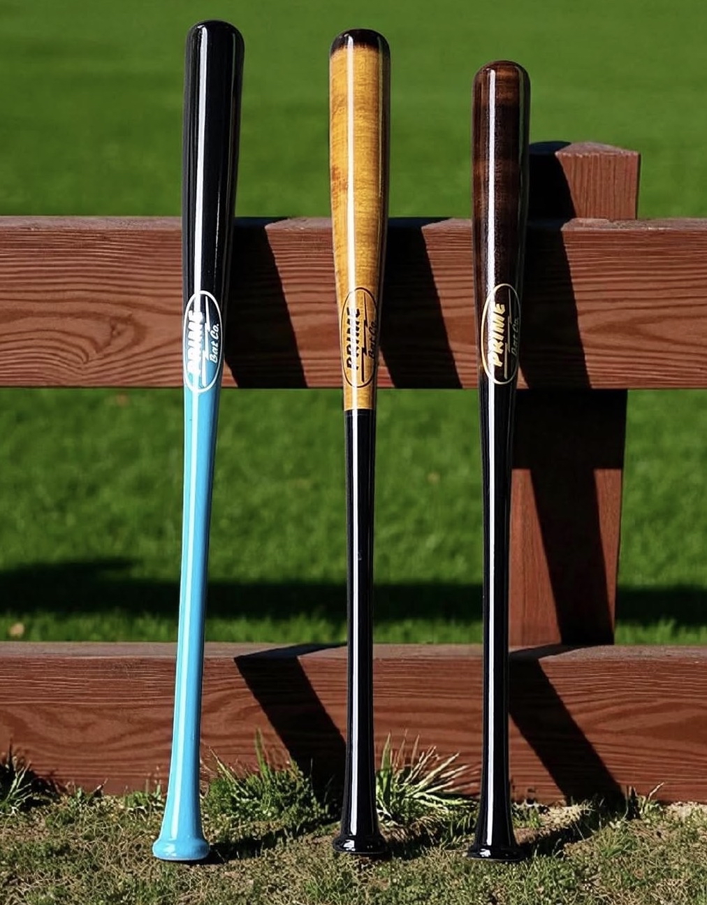 Three Prime Bat Co wood bats displayed on a fence outdoors